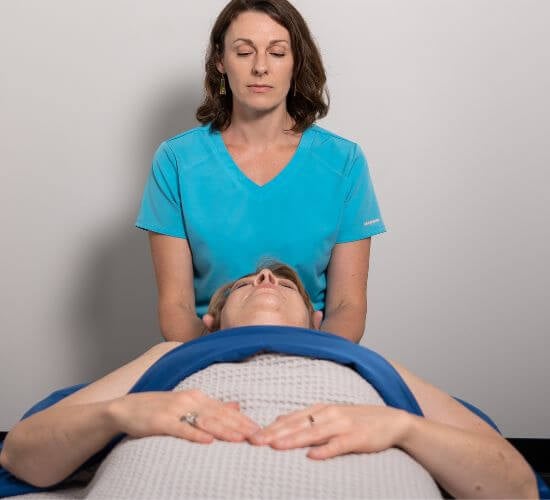 a female therapist massages the neck of a client during a relaxation massage