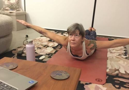 Claire performing a pose while laying on stomach with arms up